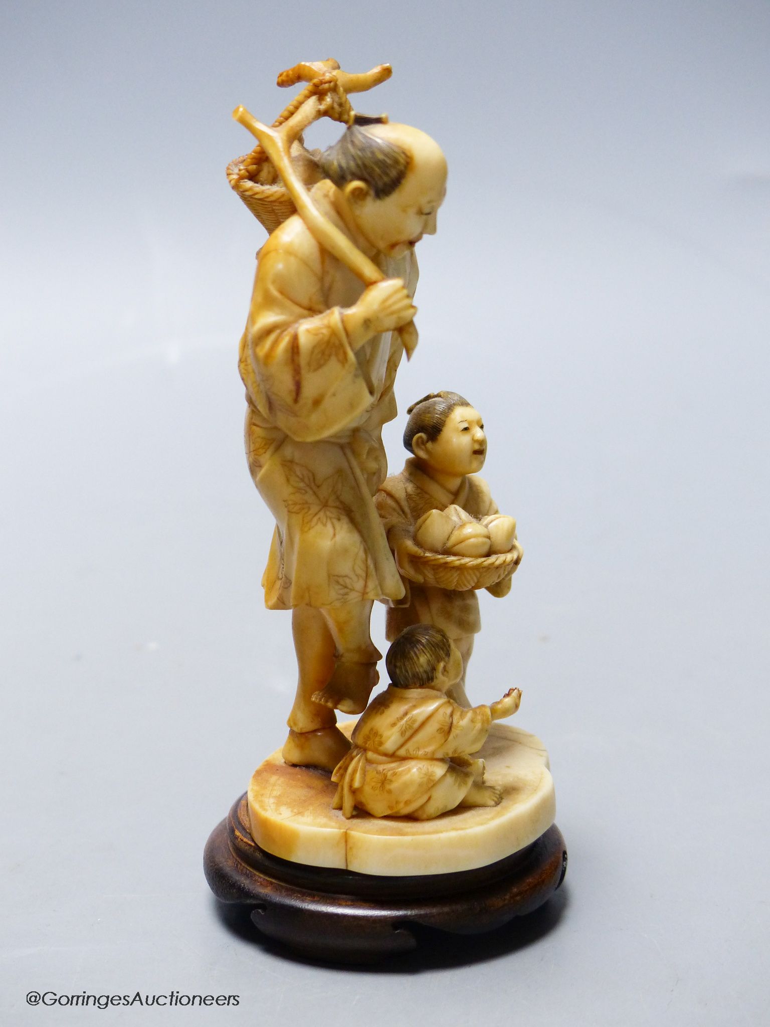 A Japanese ivory okimono of a peach seller
